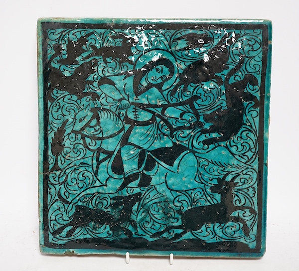 A large Persian turquoise and black tile of a female archer mounted on a horse, 26cm x 27cm. Condition - some pitting in manufacture and small crack to the edge